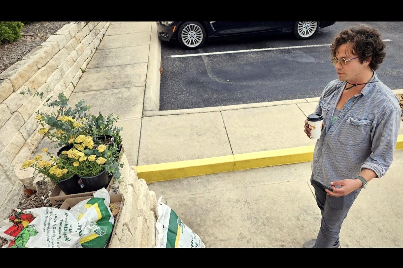 Dorian Dégagé (Dorian Degage) — surveying a curbside bioswale planting install with coffee in hand, San Antonio, Texas